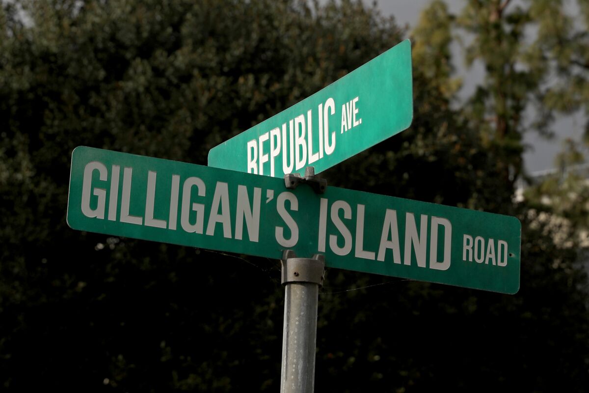 Two crossing green street signs read Gilligan's Island Road and Republic Avenue.