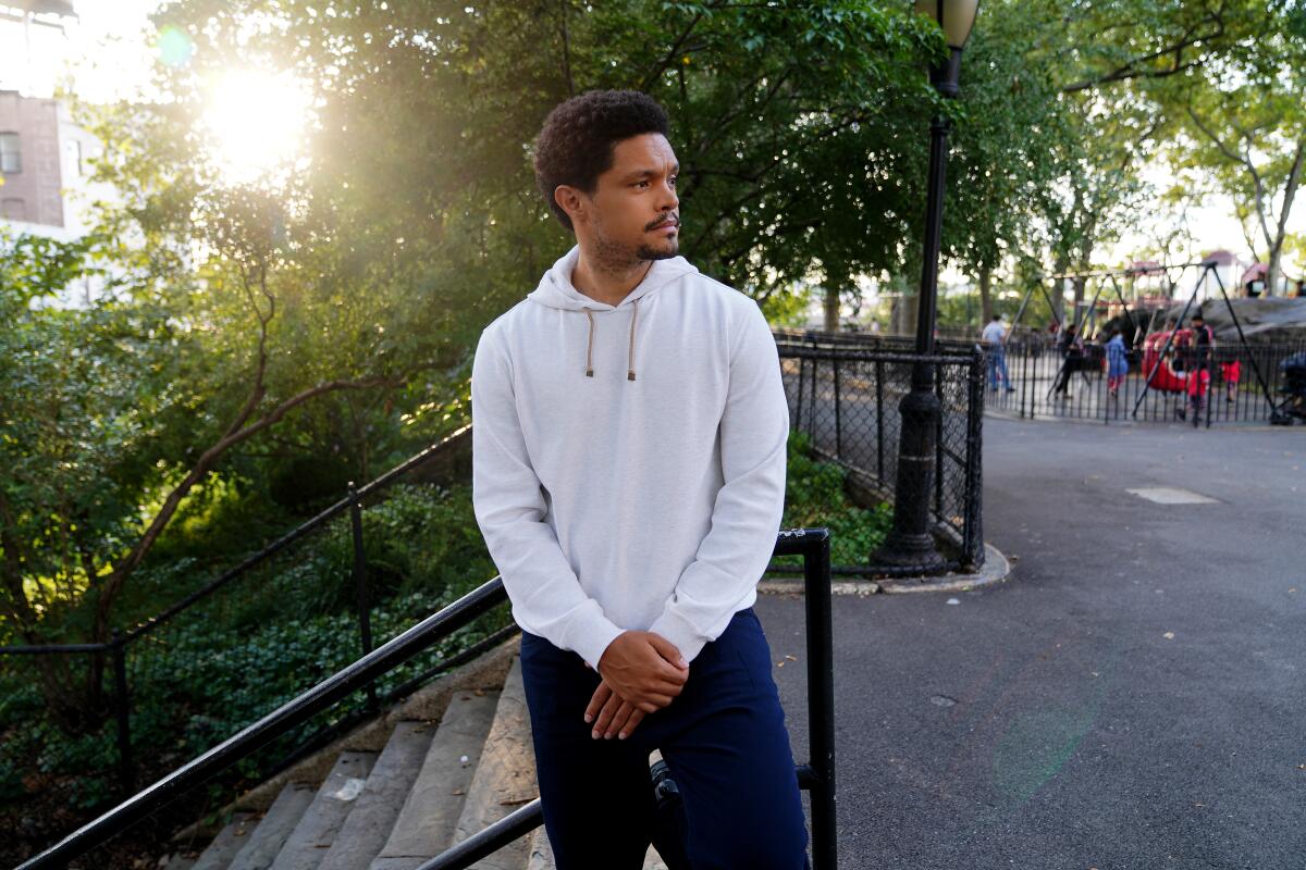Trevor Noah of 'The Daily Show' poses in a sweatshirt in a park.