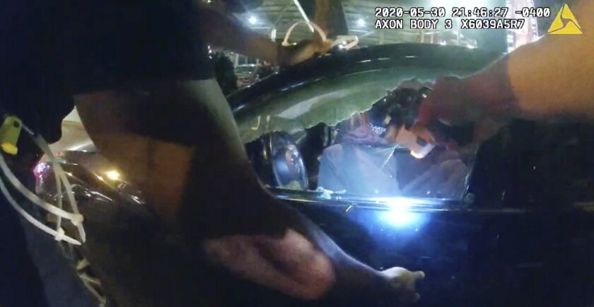 In this Saturday, May 30, 2020, photo taken from police body camera video released by the Atlanta Police Department, an officer points his handgun at Messiah Young while the college student is seated in his vehicle, in Atlanta. The following day, Atlanta's mayor two police officers were fired and three others placed on desk duty over excessive use of force during the arrest of Young and fellow college student Taniyah Pilgrim, seated in the passenger side of the car. (Atlanta Police Department via AP)