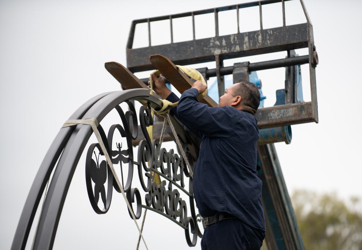 Saul Toxicoia ties a new archway for a secret garden at Huntington Central Park to a forklift Friday.