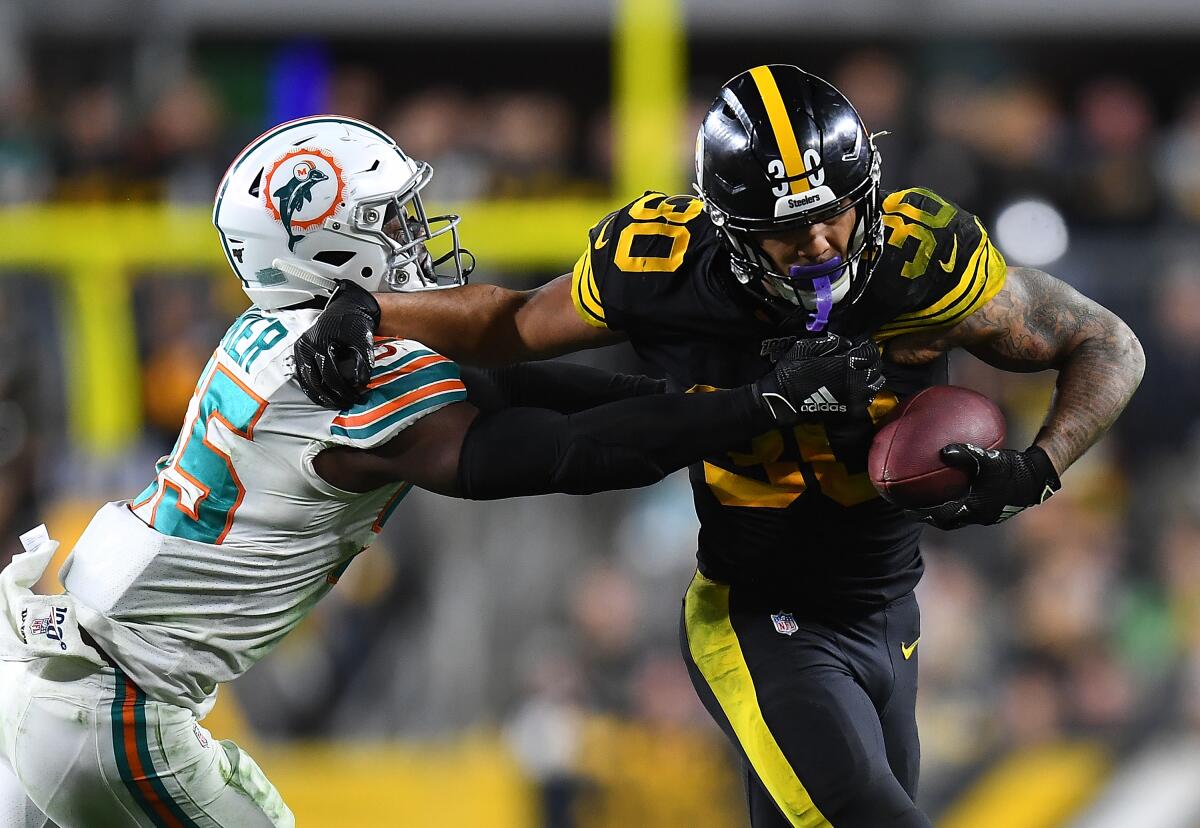 Steelers running back James Conner tries to fend off Dolphins linebacker Jerome Baker on Oct. 28, 2019.