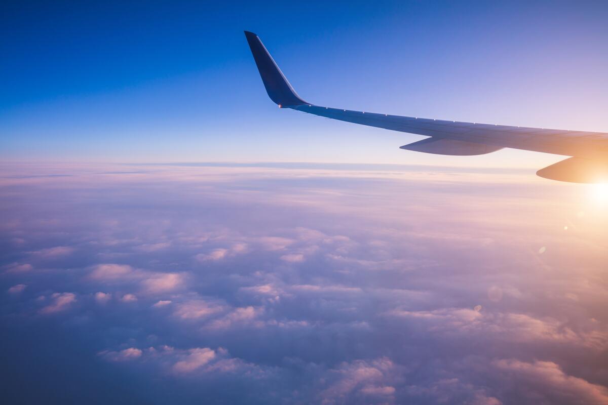 The tail of a plane in flight above clouds