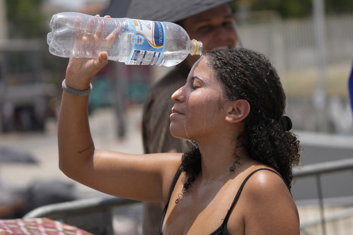A woman pours a bottle of water over her head.