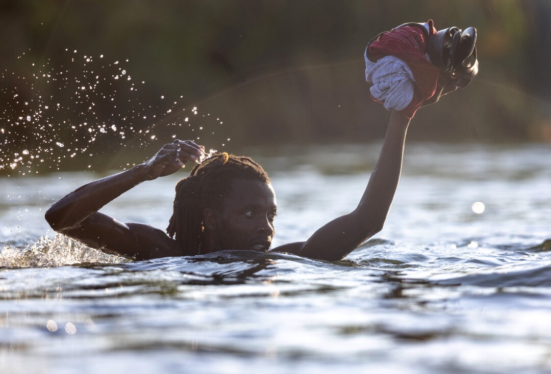 A Haitian immigrant is up to his chin in water as he crosses the Rio Grande back into Mexico.