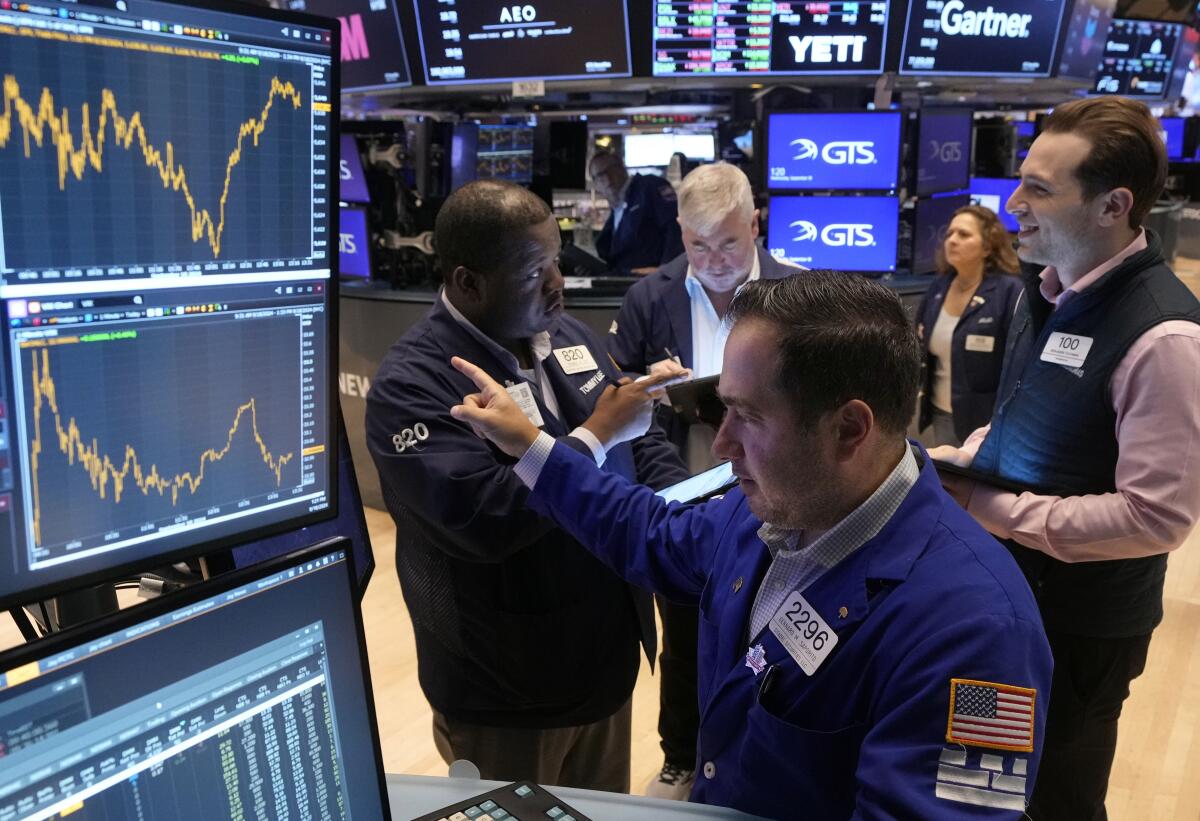 Specialist Genaro Saporito, foreground, works with traders at his post on the floor of the New York Stock Exchange.