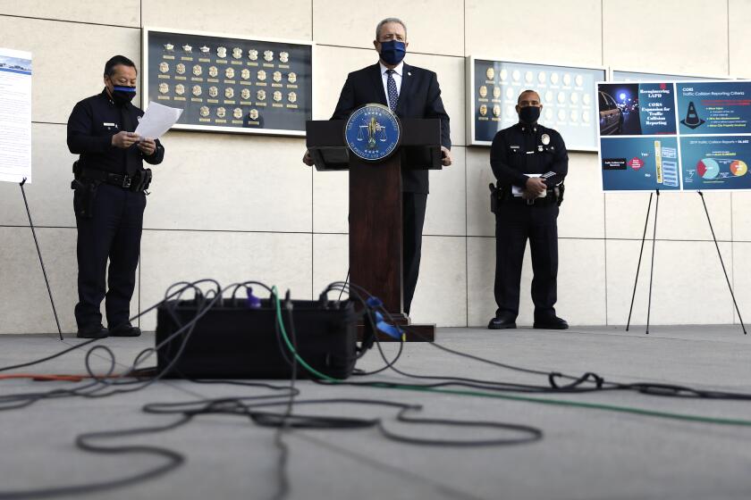 LAPD Chief Michel Moore, center, and Deputy Chief Blake Chow, left, announce a new Alternative Dispatch program