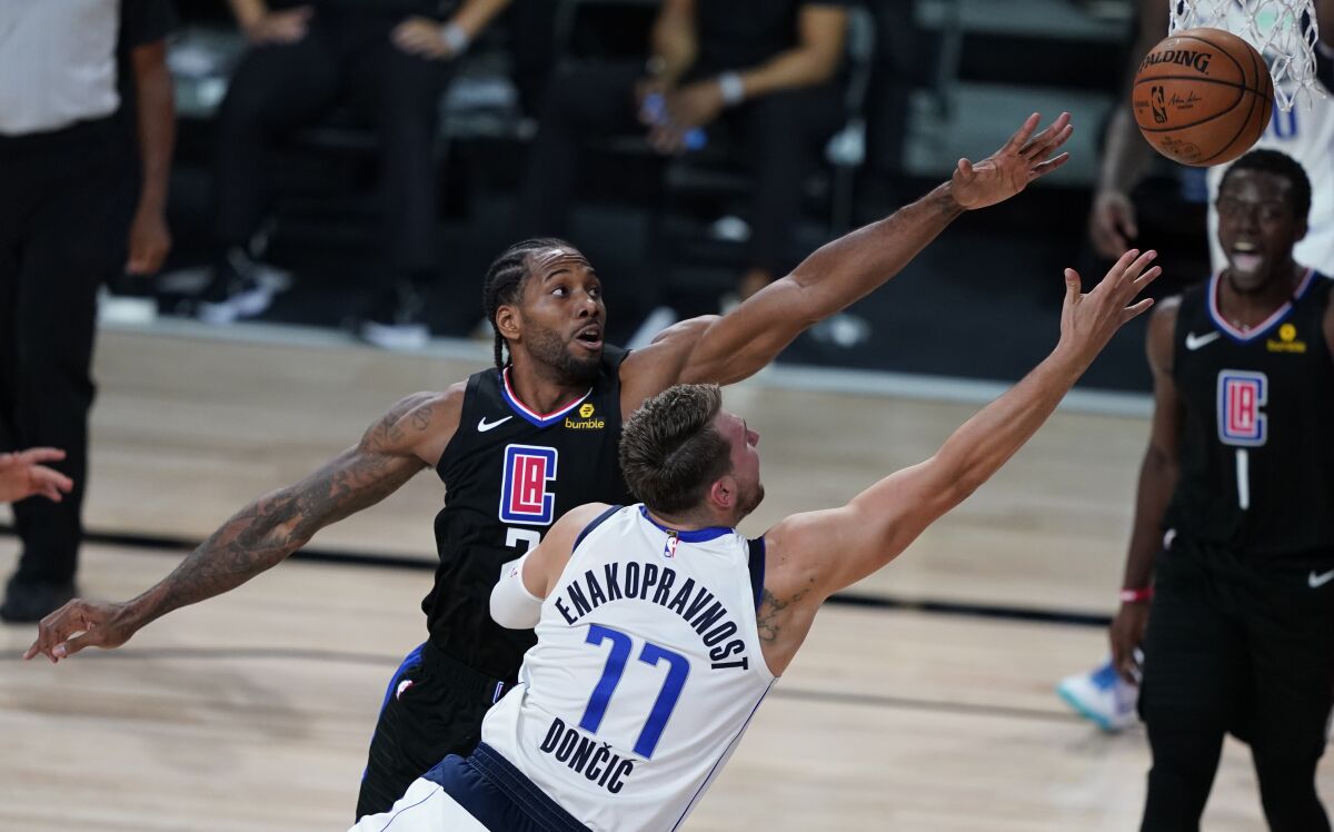 Clippers forward Kawhi Leonard, top, fouls Dallas Mavericks guard Luka Doncic.