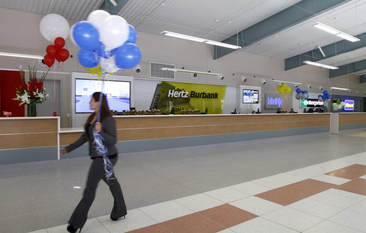 A woman carrying balloons passes by the new car rental center during grand opening of the new Regional Intermodal Transportation Center at Bob Hope Airport in Burbank on Friday, June 27, 2014.