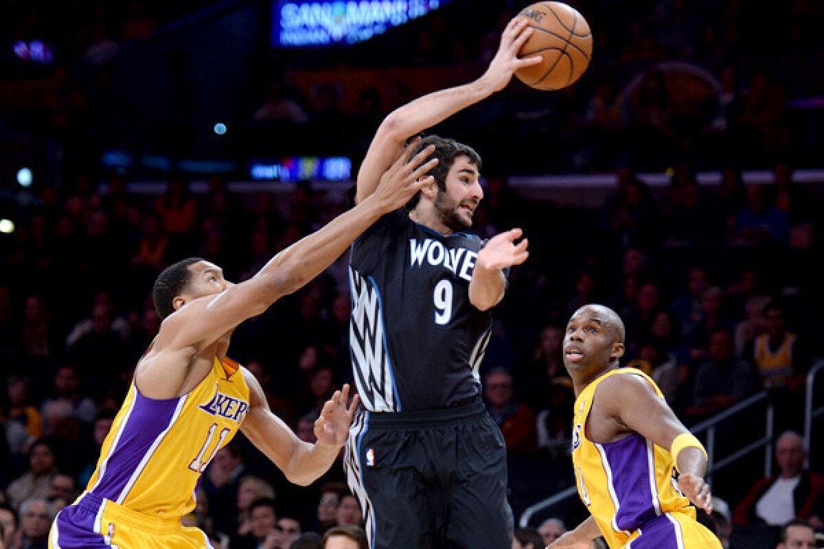 Timberwolves point guard Ricky Rubio flips a pass between Lakers forward Wesley Johnson (11) and guard jodie Meeks during a game at Staples Center.