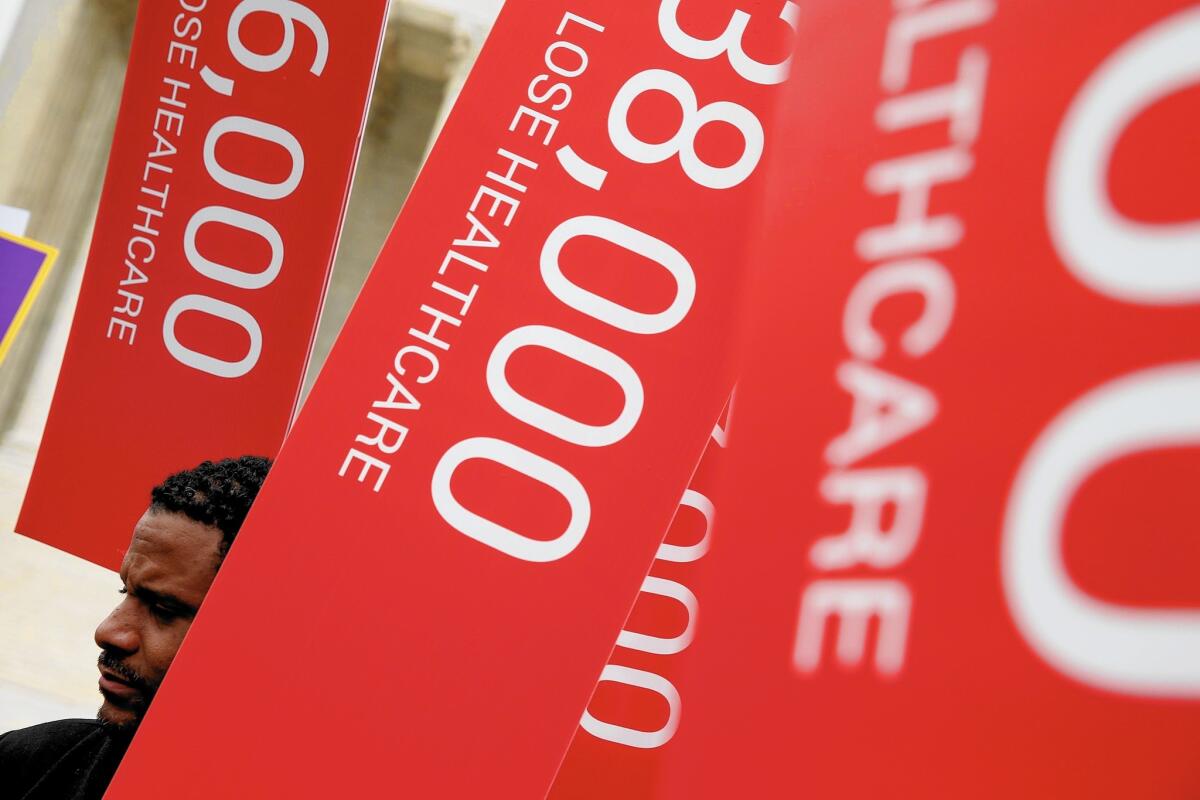 Protesters outside the Supreme Court in March carry signs depicting the number of people who have lost healthcare coverage.