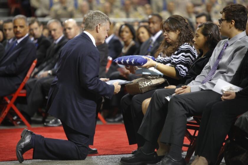 Ana Hernandez accepts the U.S. flag from acting Department of Homeland Security Secretary Rand Beers during the public memorial service for her husband, slain TSA officer Gerardo Hernandez.