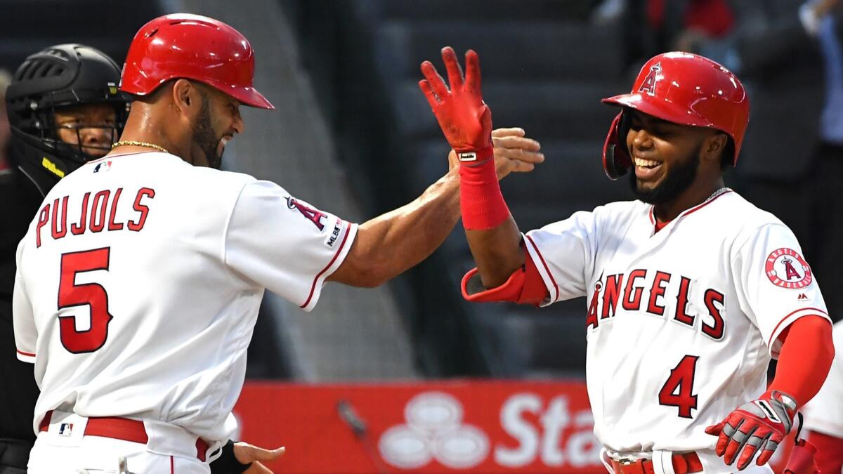 Angels' Luis Rengifo (4) gets a high five from Albert Pujols (5) after hitting a three-run home run against the Cincinnati Reds in the second inning at Angel Stadium on Tuesday.