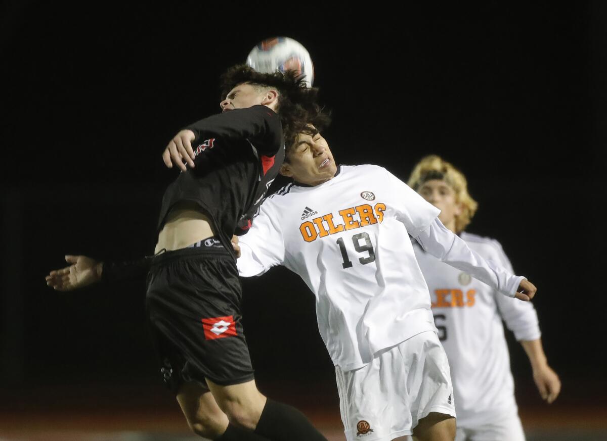 Mario Hernandez (19), right, of Huntington Beach goes up against San Clemente's Niko Kaczmarczyk (10) at midfield.