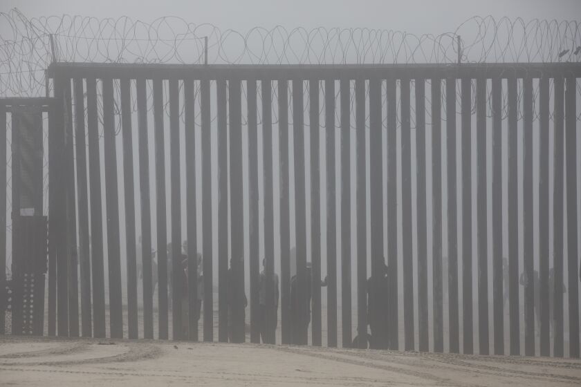 San Diego, CA - September 07: People peer through the border fence in Tijuana, Mexico to San Diego, California on Wednesday, Sept. 7, 2022. (Ana Ramirez / The San Diego Union-Tribune)