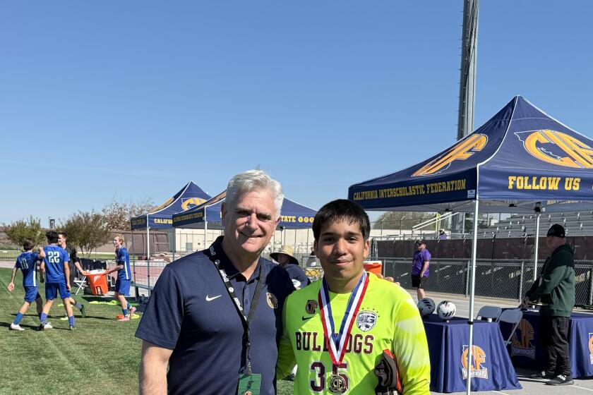 Garfield goalkeeper Javier Zarate gets his photo taken with CIF executive director Ron Nocetti at state soccer finals.