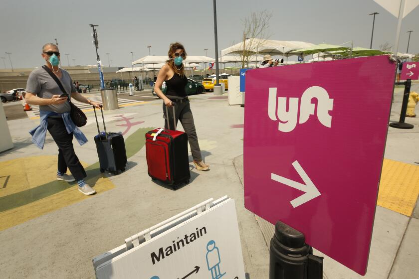 LAX AIRPORT, CA - AUGUST 20: Passengers make their way to the rideshare location at LAX as Uber and Lyft drivers held a moving rally as part of a statewide day of action to demand that both ride-hailing companies follow California law and grant drivers "basic employee rights" and to "denounce the corporations' efforts to avoid their responsibilities to workers." Uber and Lyft threatened to suspend services in California Thursday night but a court granted Uber and Left a stay to a preliminary injunction requiring both rideshare companies to reclassify their drivers as employees, meaning the rideshare companies will not suspend service in California tonight as they threatened. Los Angeles on Thursday, Aug. 20, 2020 in LAX Airport, CA. (Al Seib / Los Angeles Times