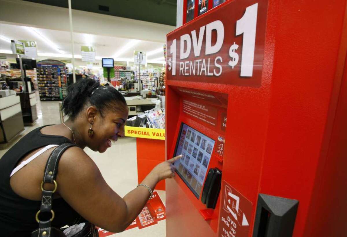 A woman selects a DVD at a Redbox kiosk in 2009. The company will be sold to Apollo Global Management for $1.6 billion.