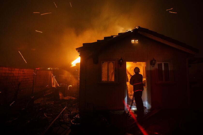 Patrick T. Fallon??For The Times FIRE CREWS enter a house engulfed in flames as the Saddleridge fire spreads quickly early Friday morning.