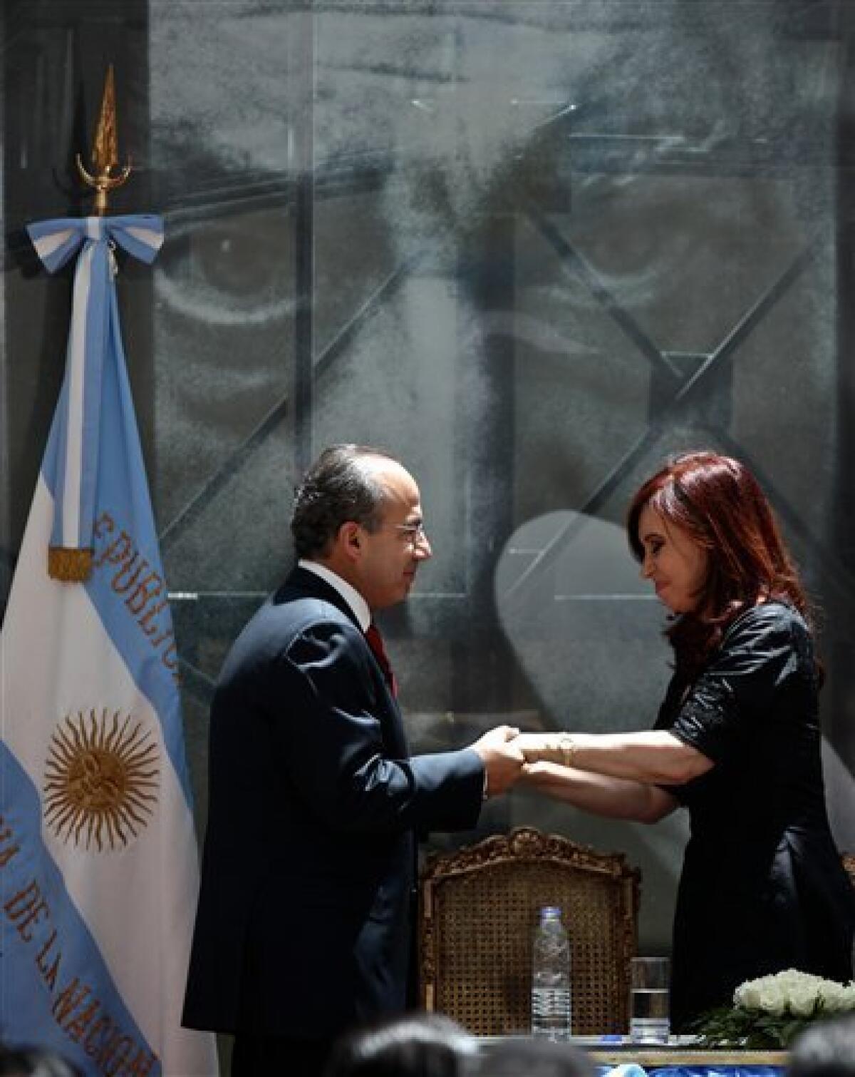 Mexico's President Felipe Calderon, left, and Argentina's President Cristina Fernandez talk back dropped by a photograph of Mexican artist David Alfaro Siqueiros, after inaugurating a mural painted by Siqueiros at the government house in Buenos Aires, Argentina, Friday, Dec. 3, 2010. The mural entitled "Ejercicio Plastico", has been placed at the future Museum of Political Arts, a former underground customs facility next to the government house. (AP Photo/Ivan Fernandez)