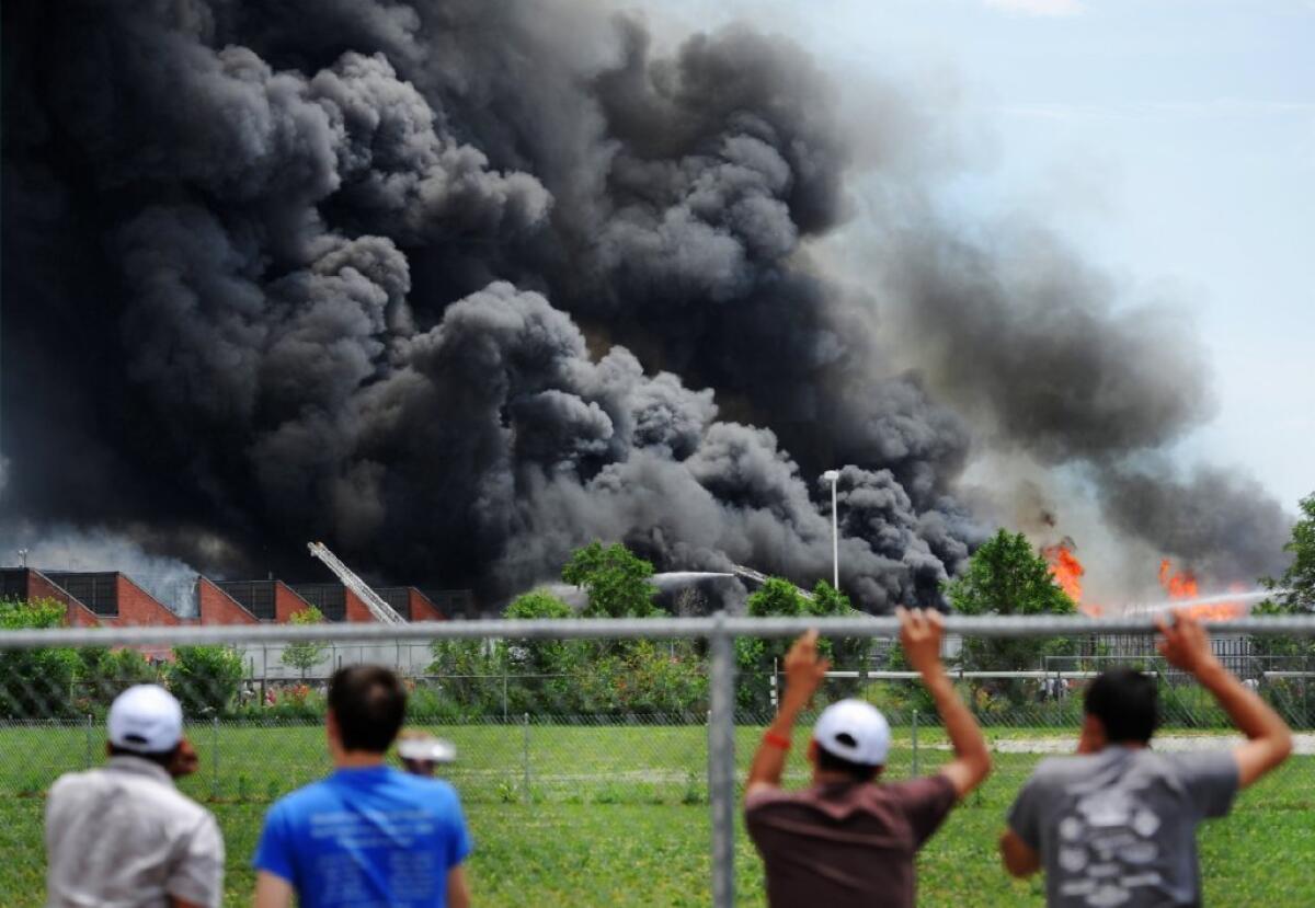 Spectators watch a fire engulf a sprawling mixed-use building near downtown Indianapolis filled with tires and wooden pallets Saturday. The fire was expected to continue smoldering for several days, authorities said.