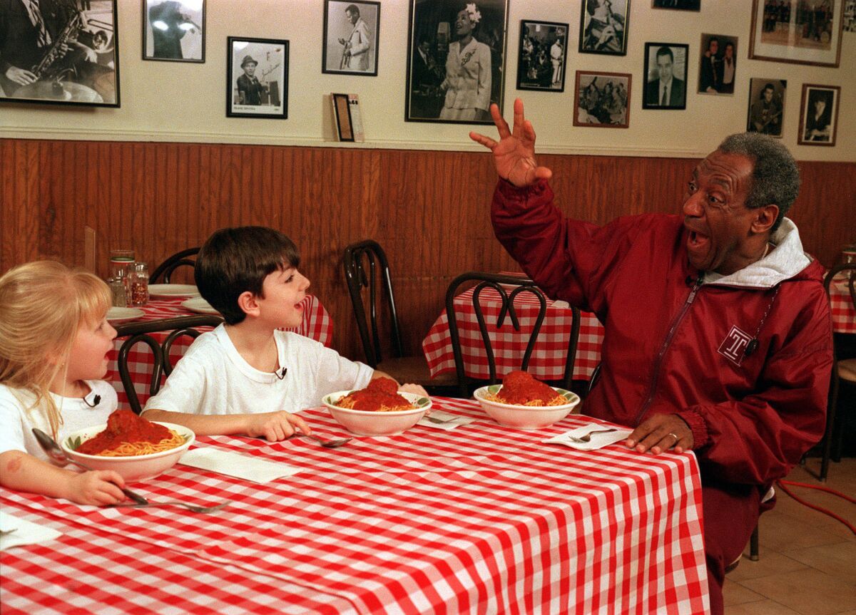 Bill Cosby has fun eating spaghetti with his friends Brooke Dolega (blonde) and Cameron Hunt, in the CBS series, KIDS SAY THE DARNDEST THINGS, which ran 1998-2000.