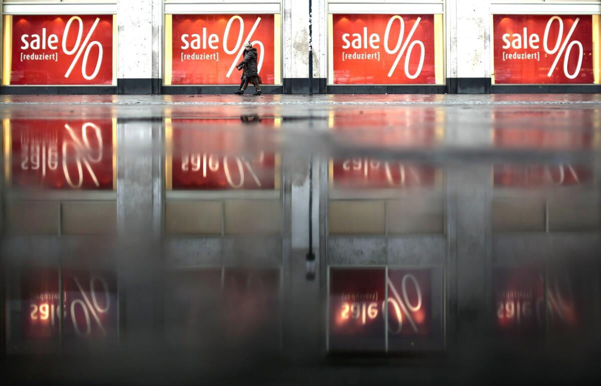 Pedestrians walk in front of sales posters displayed at a department store in Berlin Jan. 7. The OECD says global inflation fell in November to 1.5%, fueling concerns about a global economic slowdown.