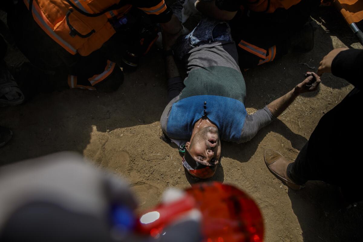 A Palestinian man grimaces as he is treated by medics after being shot during a protest dubbed the Great March of Return at the border fence separating Israel and Gaza.