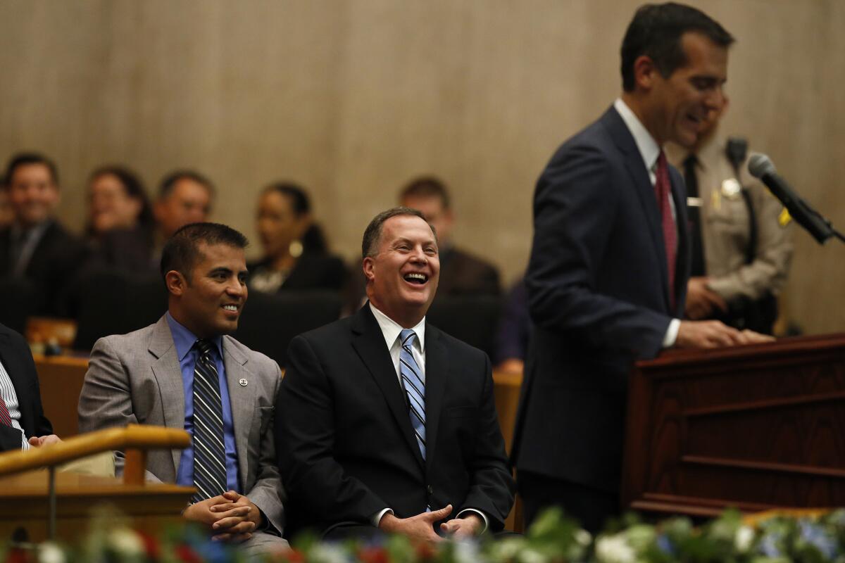 L.A. County Assessor Jeffrey Prang, center, along with his husband Ray Vizcarra, left, laugh during a speech by Los Angeles Mayor Eric Garcetti during his oath of office ceremony at the Hall of Administration in downtown L.A. last December.