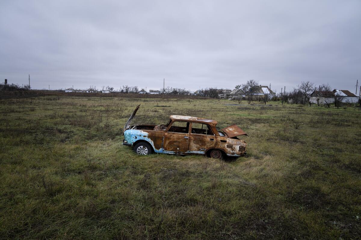 A destroyed car sits in a field