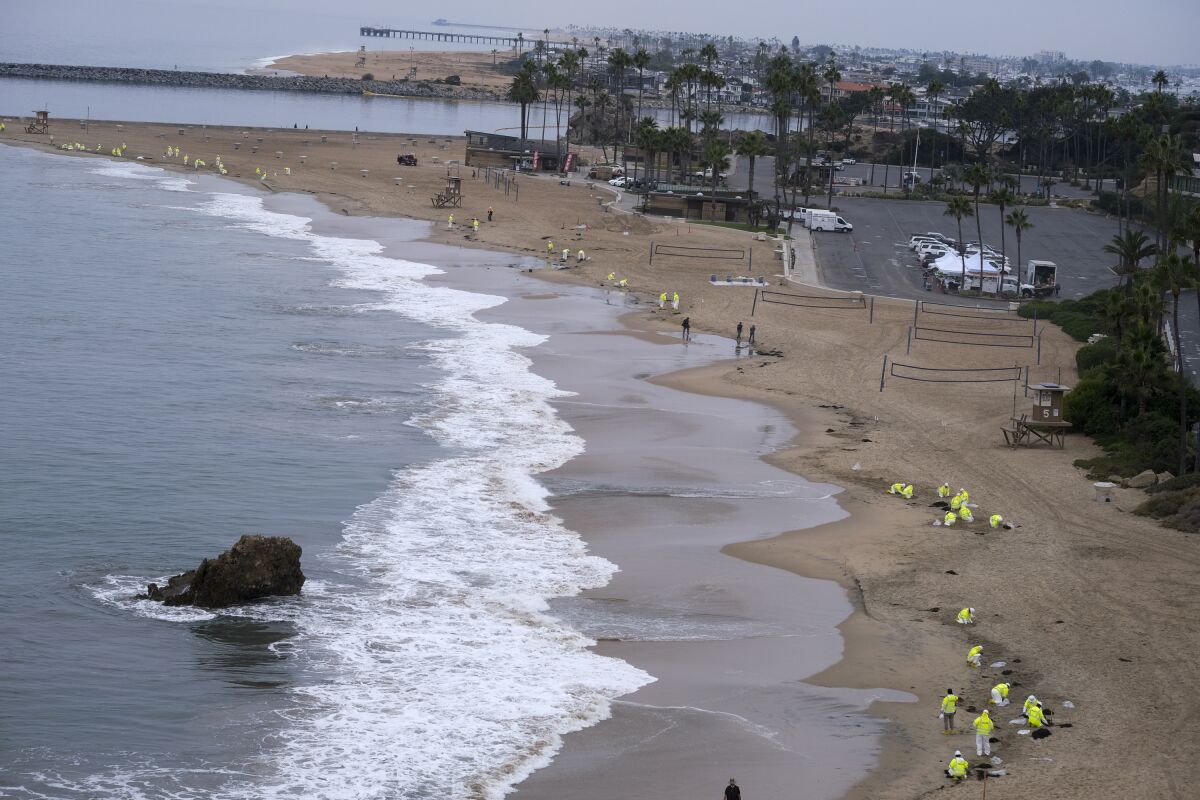FILE - In this Thursday, Oct 7, 2021 file photo, Workers in protective suits clean the contaminated beach in Corona Del Mar after an oil spill in Newport Beach, Calif. California's uneasy relationship with the oil industry is being tested again by the latest spill to foul beaches and kill birds and fish off Orange County. (AP Photo/Ringo H.W. Chiu, File)