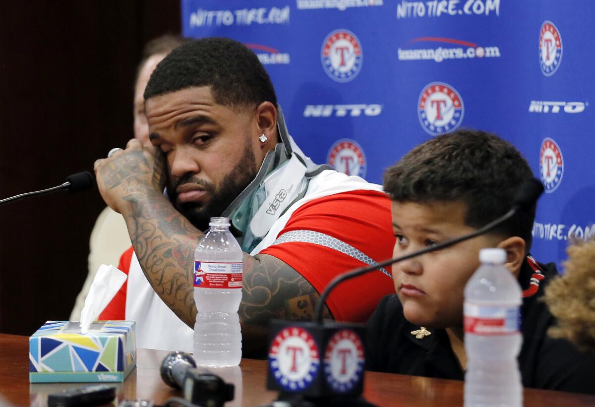 Rangers first baseman Prince Fielder, left, wipes his eyes as he sits by his son Haven during a news conference to announce his medical retirement from baseball.