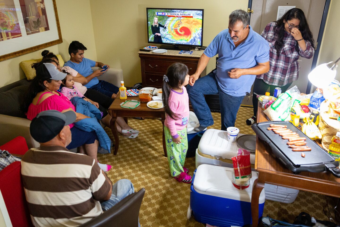 The Ramos family prepares dinner and watches the weather forecast in their hotel room Thursday night in Wilmington, N.C., where they will wait out Hurricane Florence.
