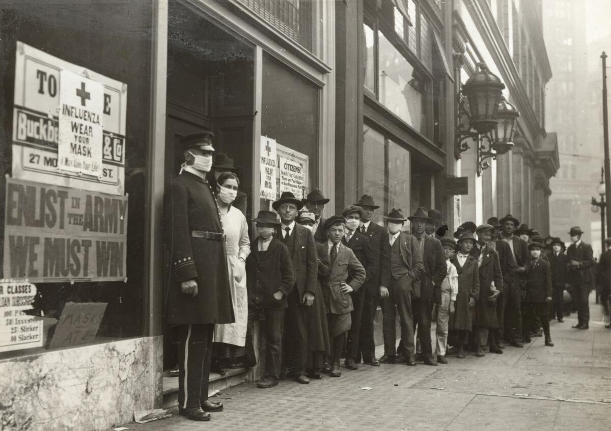 A handout picture provided by the California State Library shows people waiting in line to get flu masks on Montgomery Street in San Francisco in 1918. Unlike Los Angeles, San Francisco stressed mask wearing, but not social distancing during the Spanish flu pandemic.
