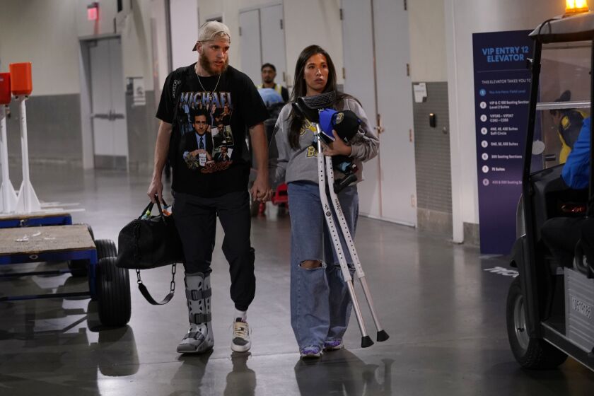 Los Angeles Rams wide receiver Cooper Kupp, left, walks out in street clothes and a boot on his foot with wife Anna