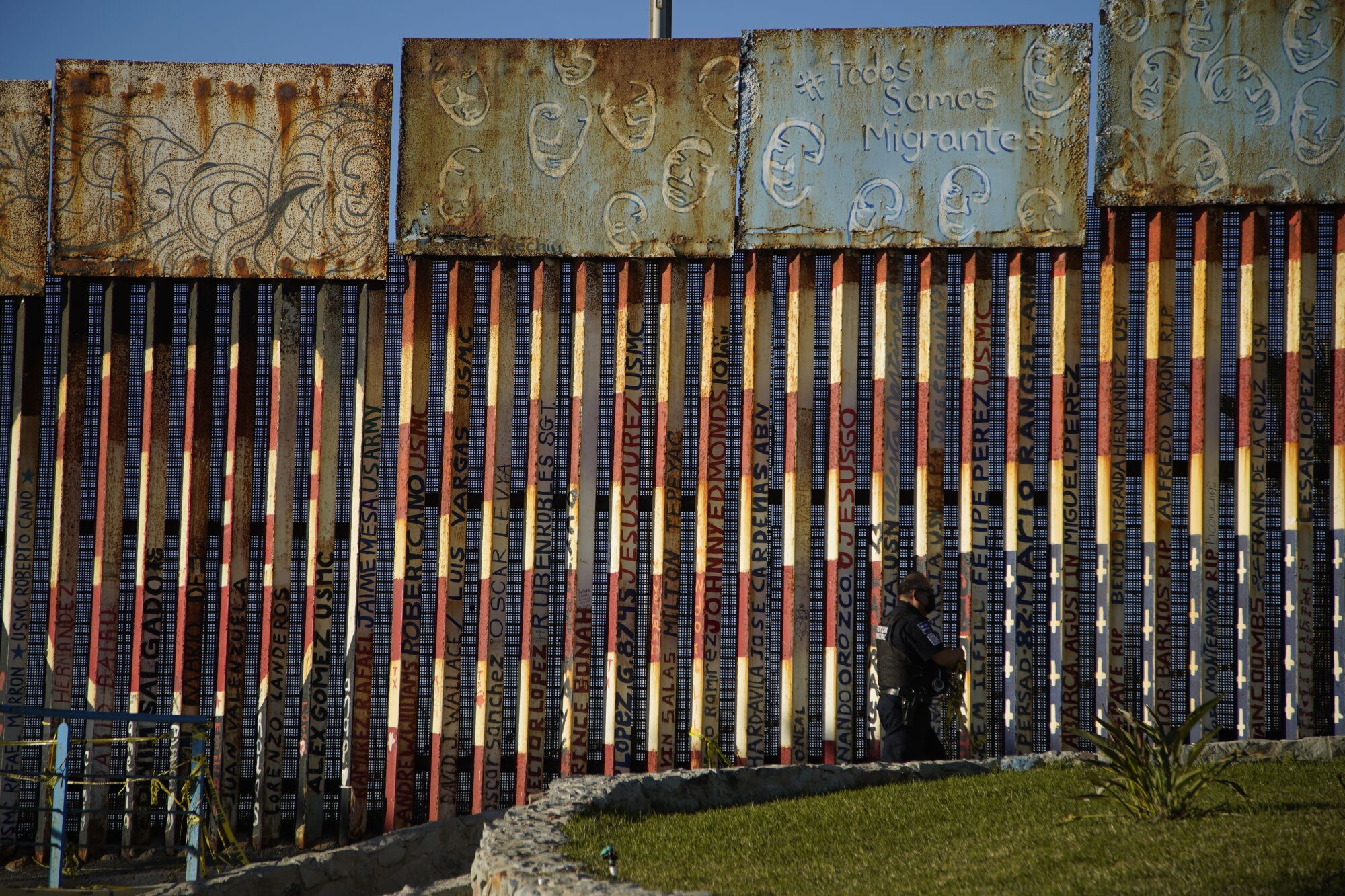 A Mexican police officer patrols near the graffiti-covered border fencing at Playas de Tijuana.
