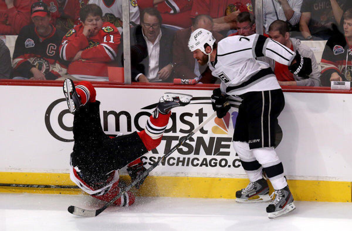 Kings defenseman Rob Scuderi (7) drops Blackhawks forward Patrick Sharp with a check along the side boards in the second period of Game 2 of the Western Conference finals.
