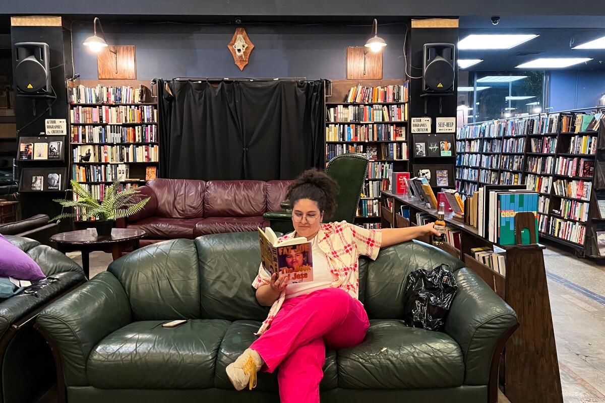 A person in pink relaxes on a couch, reading a book in a bookstore.