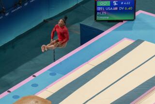 Simone Biles holds a pike position in midair, next to a monitor that displays the maneuver's 6.4 difficulty rating