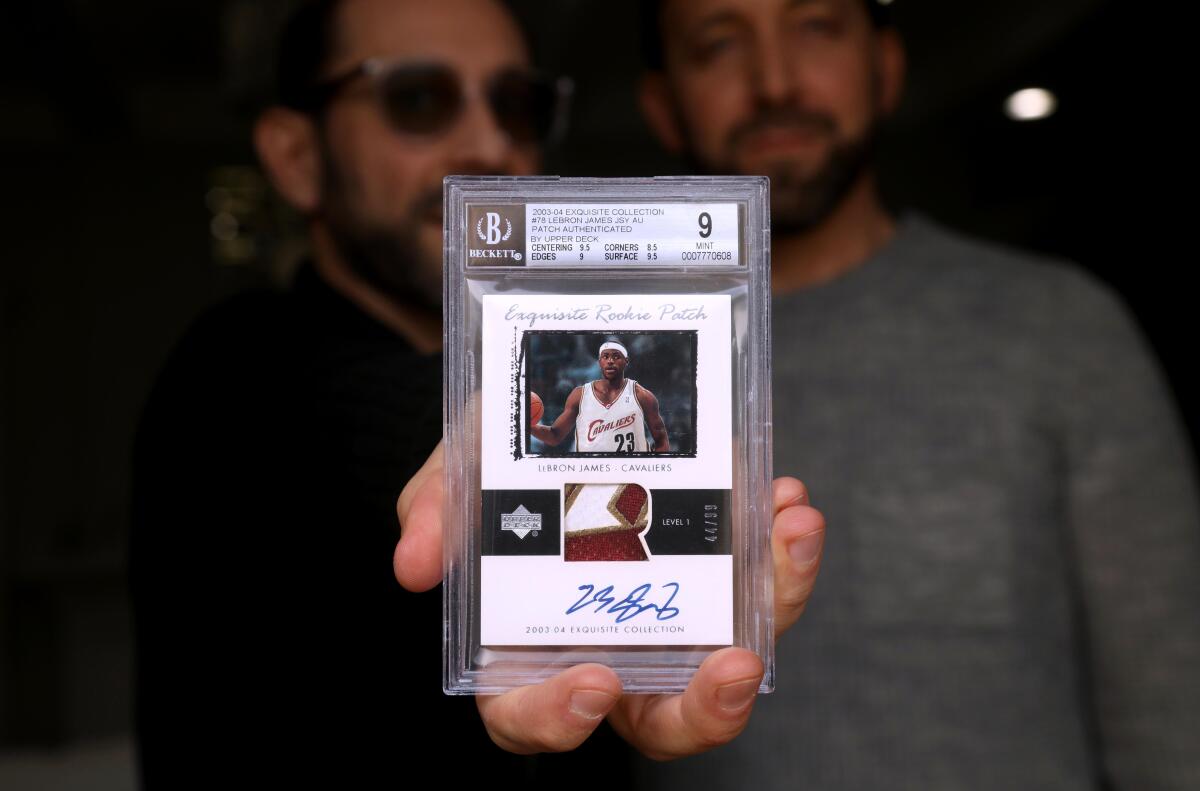 Steven Spiegel, left, next to his brother Alan, holds a LeBron James rookie card 