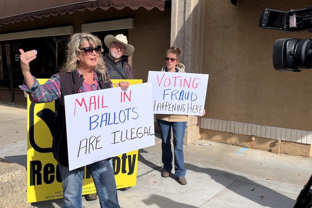 Protesters hold signs declaring voter fraud and opposing mail ballots