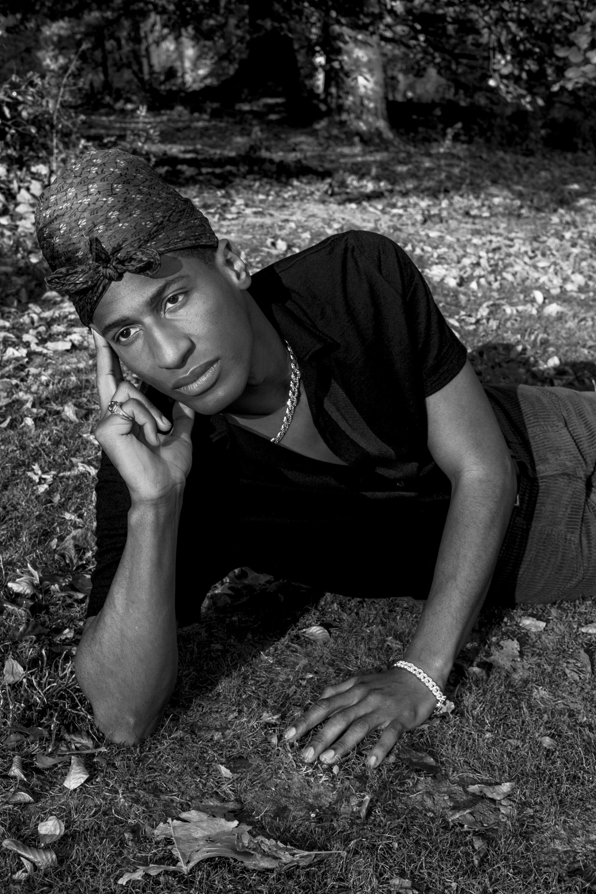  A man in a turban-esque headwrap, lying on the grass.