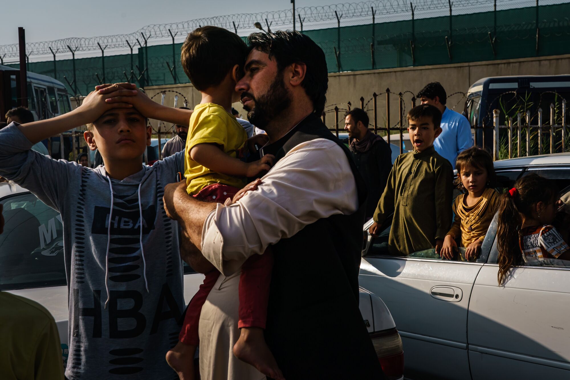A father with two boys on the road to the military entrance of the airport for evacuations in Kabul, Afghanistan.