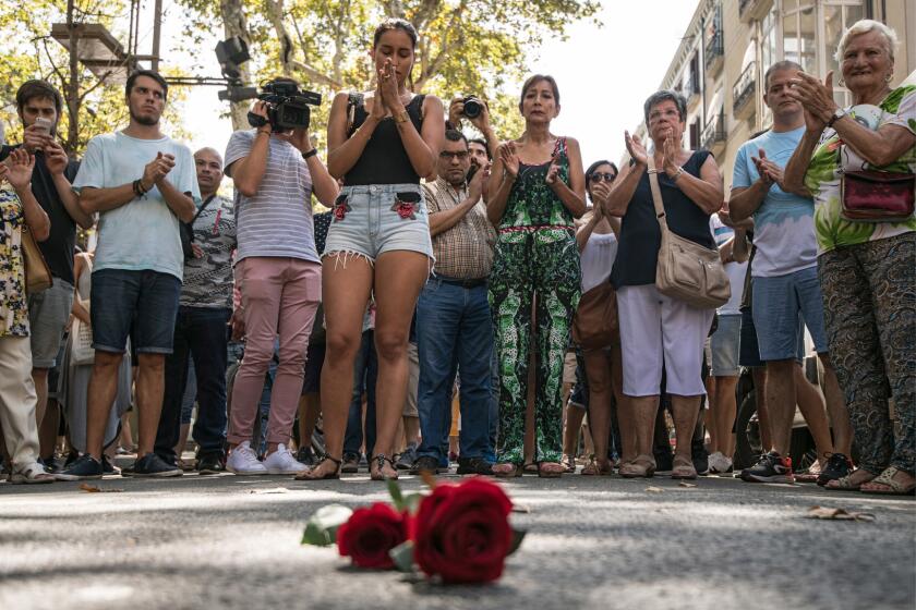 People gather around roses laid on the ground on Las Ramblas after one minute's silence for the victims of Thursday's terrorist attack in Barcelona, Spain.