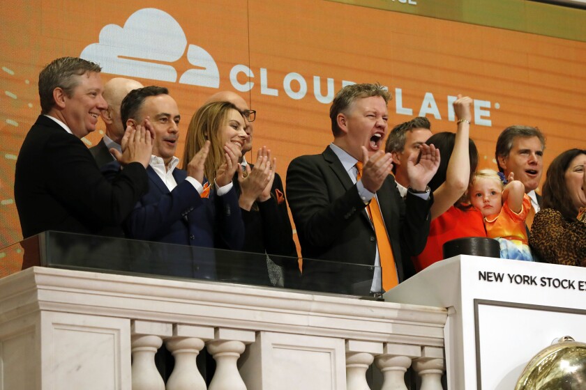 FILE - In this Sept. 13, 2019, file photo, Cloudflare co-founder and CEO Matthew Prince, right center, applauds during New York Stock Exchange opening bell ceremonies to celebrate his company's IPO. San Francisco-based Cloudflare said Wednesday, Jan. 15, 2020, it will provide free cybersecurity support to federal election campaigns. (AP Photo/Richard Drew, File)