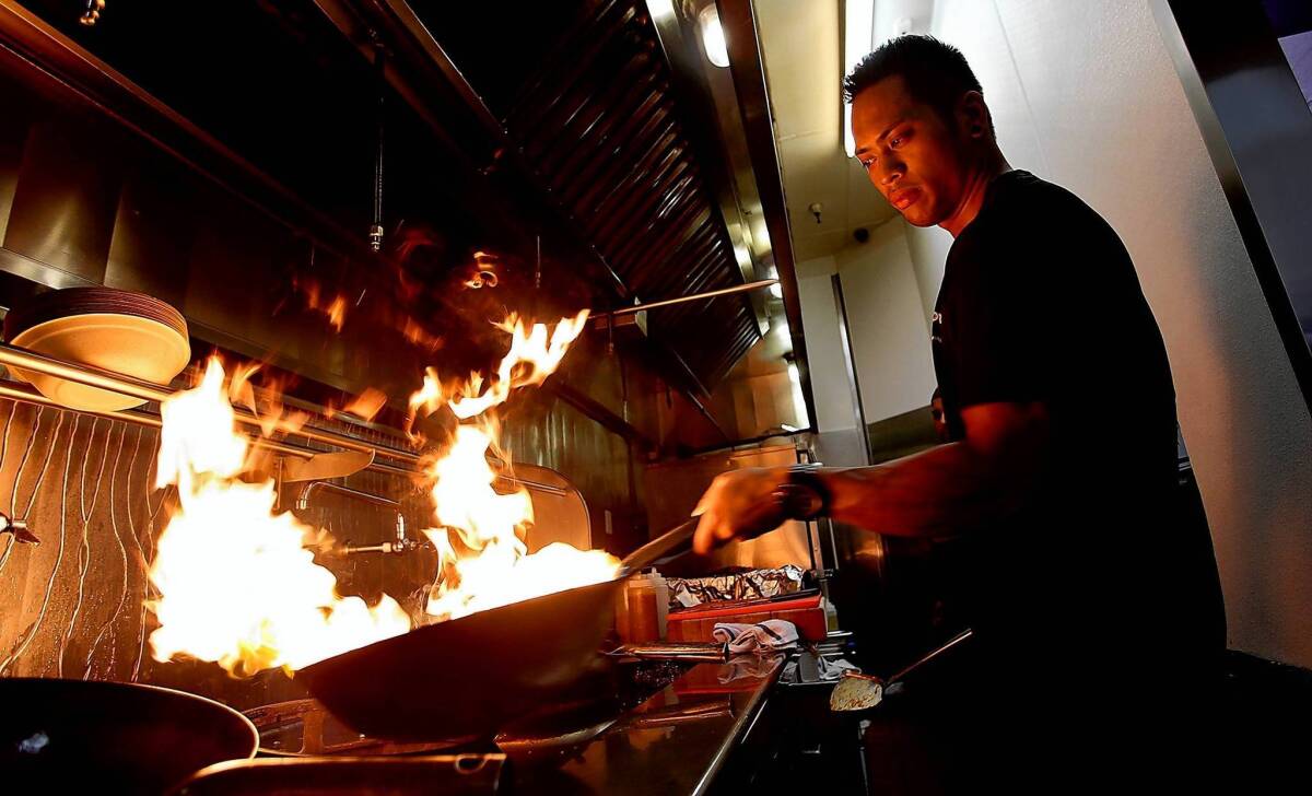 Manager and sous chef Micko Ortiz prepares a wok for cooking.