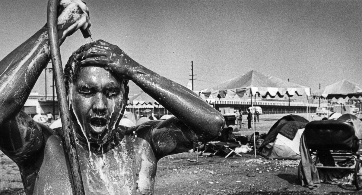 Sep. 18, 1987: Jose Lopez shampoos his hair with the help of a garden hose. He was cleaning up before going on a job search.