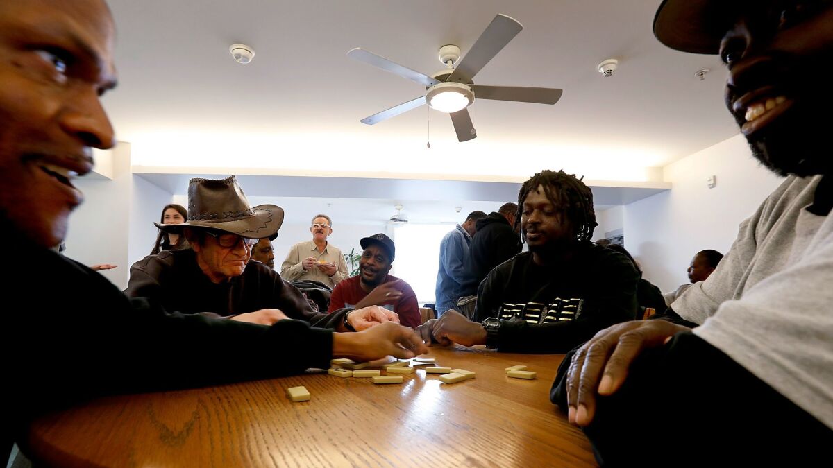 Mark Abraham, left, Carl Russell, Damon James and Anthony Donnon participate in the Skid Row Housing Trust dominoes championship tournament at the Abbey Apartments in downtown L.A. on Tuesday.