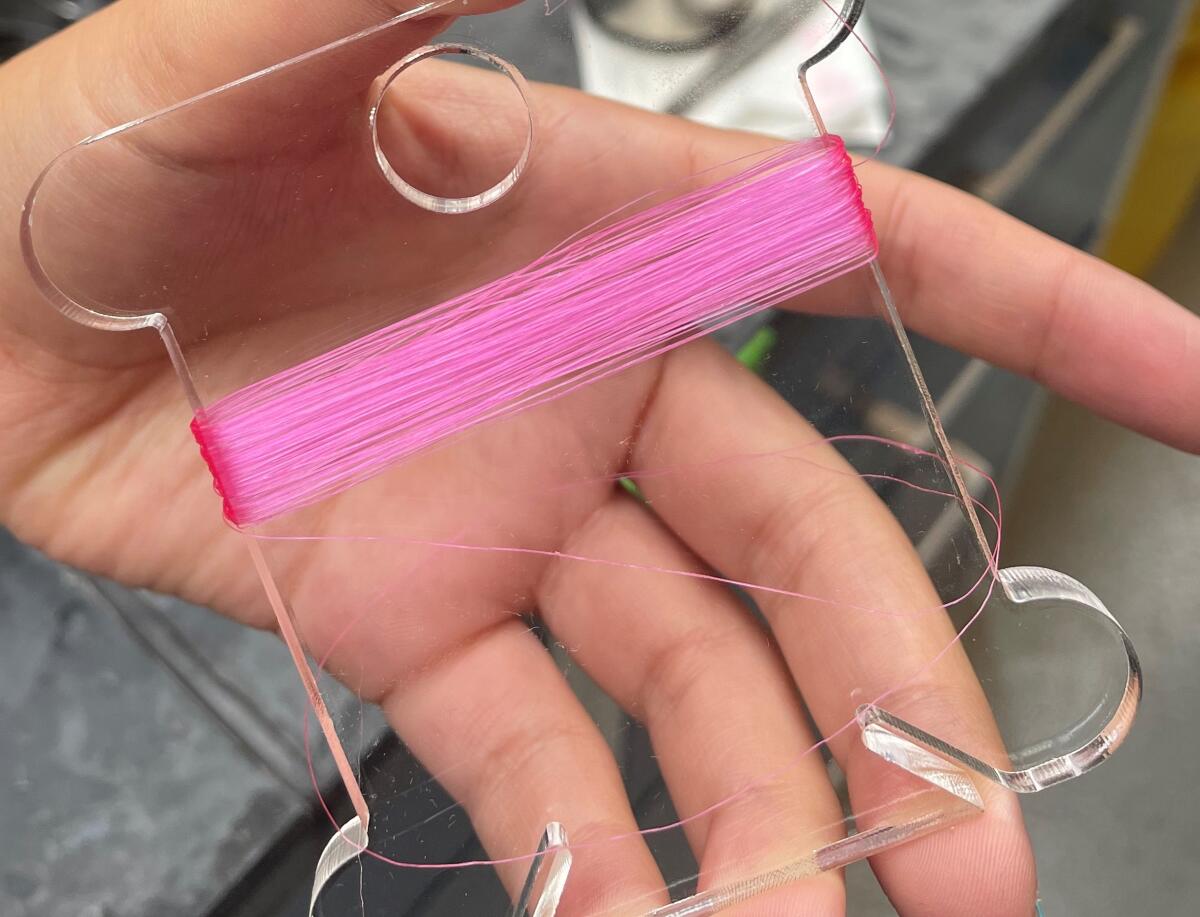 Pink fiber wrapped around a clear spool