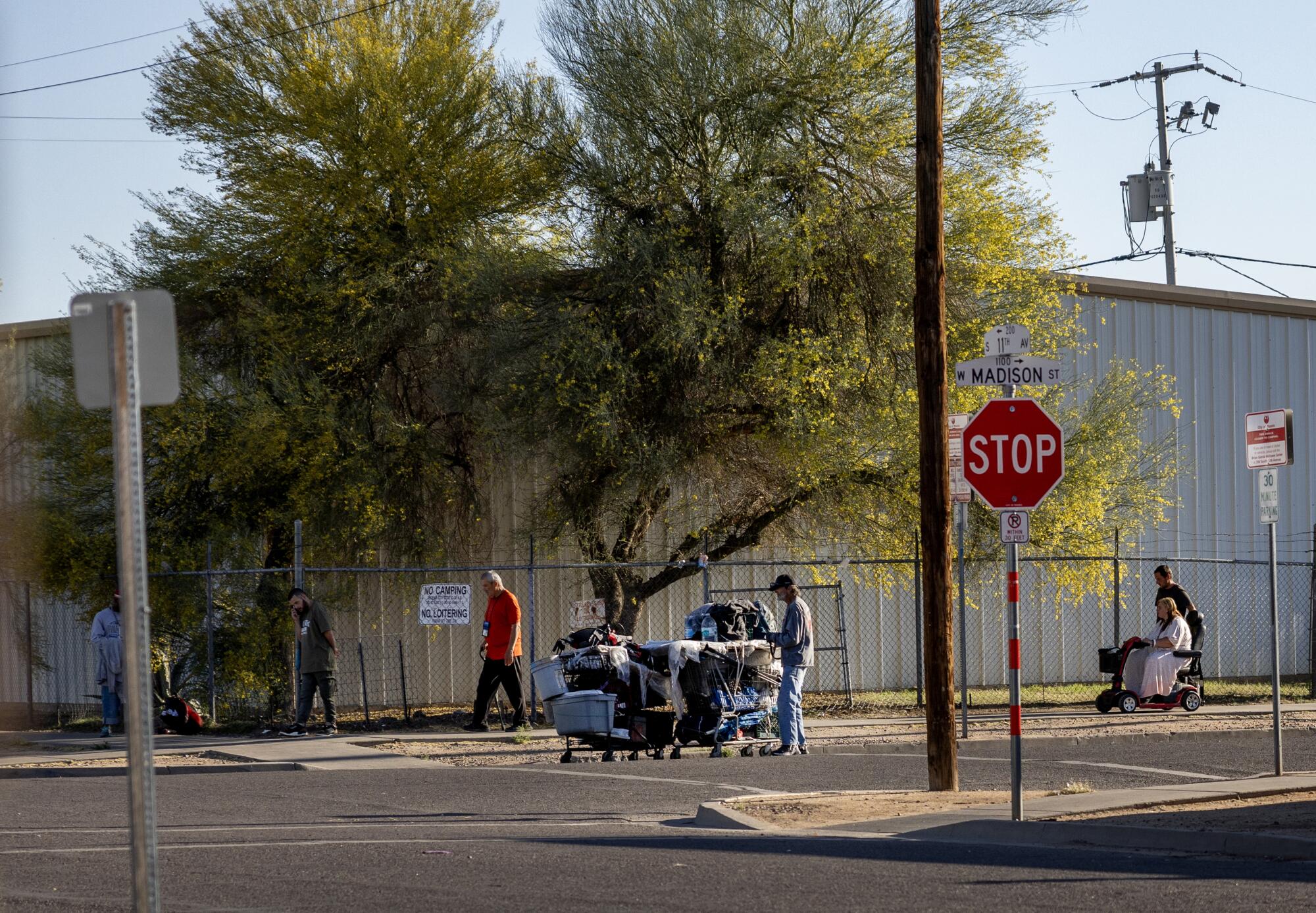 A homeless person with belongings near a stop sign 