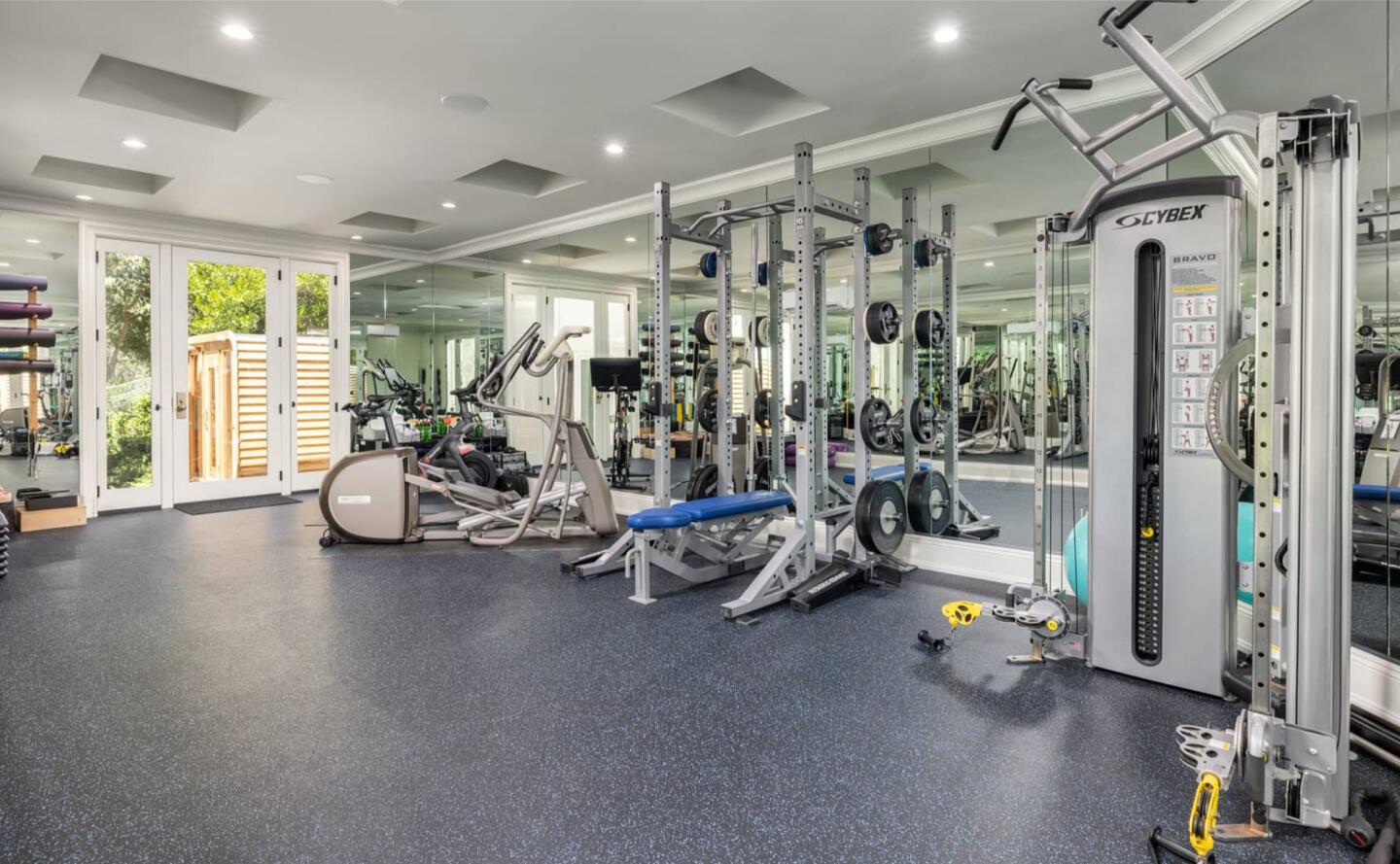 The gym has equipment and windows overlooking greenery.